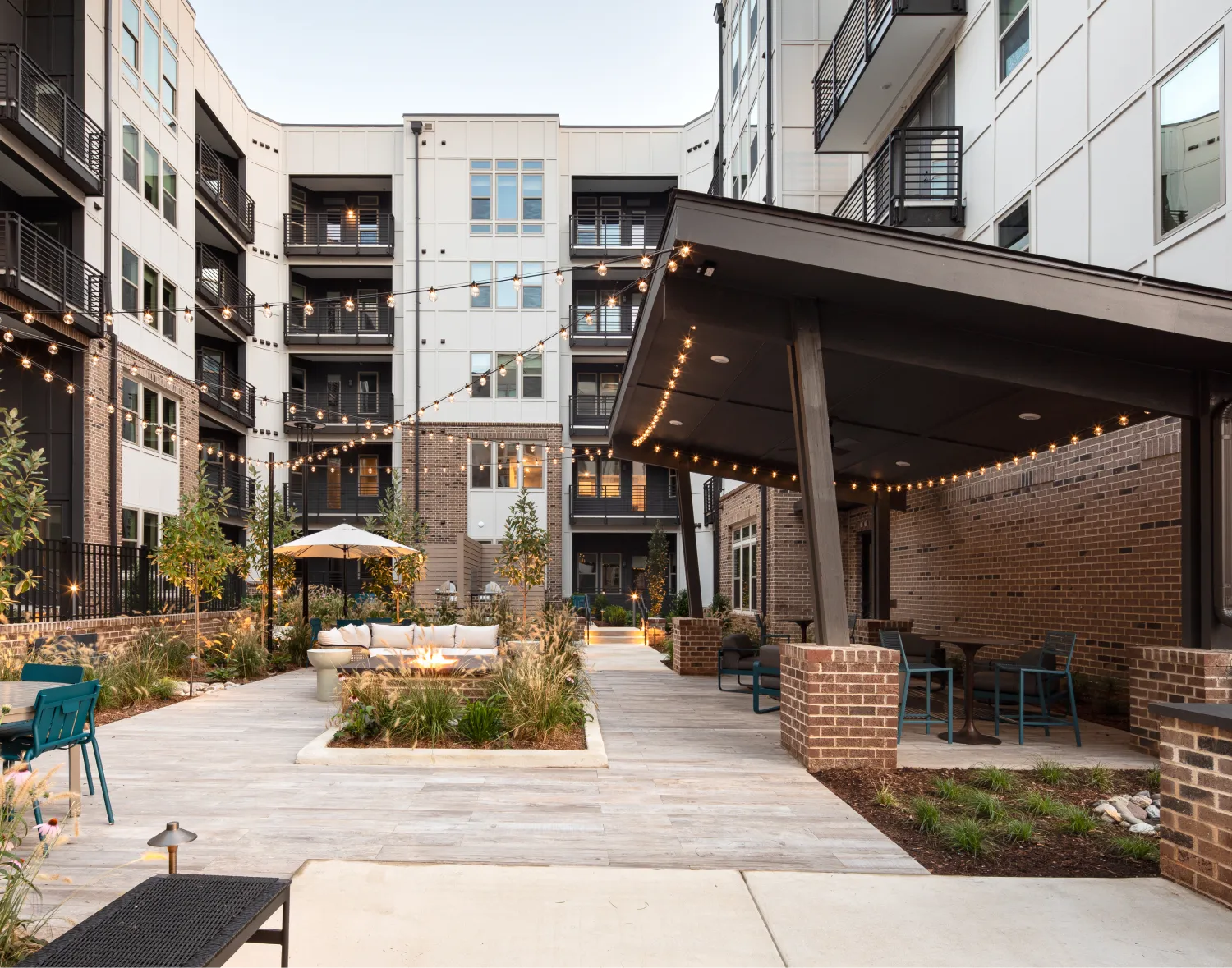 Contemporary residential community entrance featuring stylish outdoor lounge space and illuminated walkways