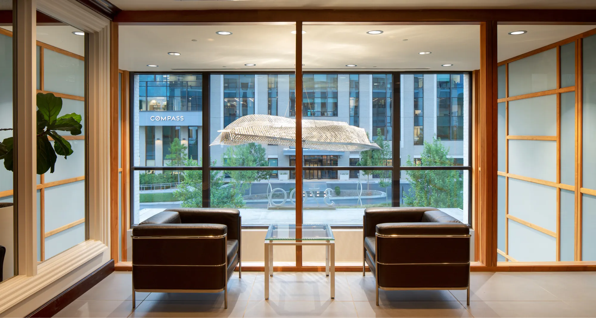 Modern waiting area with leather chairs, glass table, and expansive window views