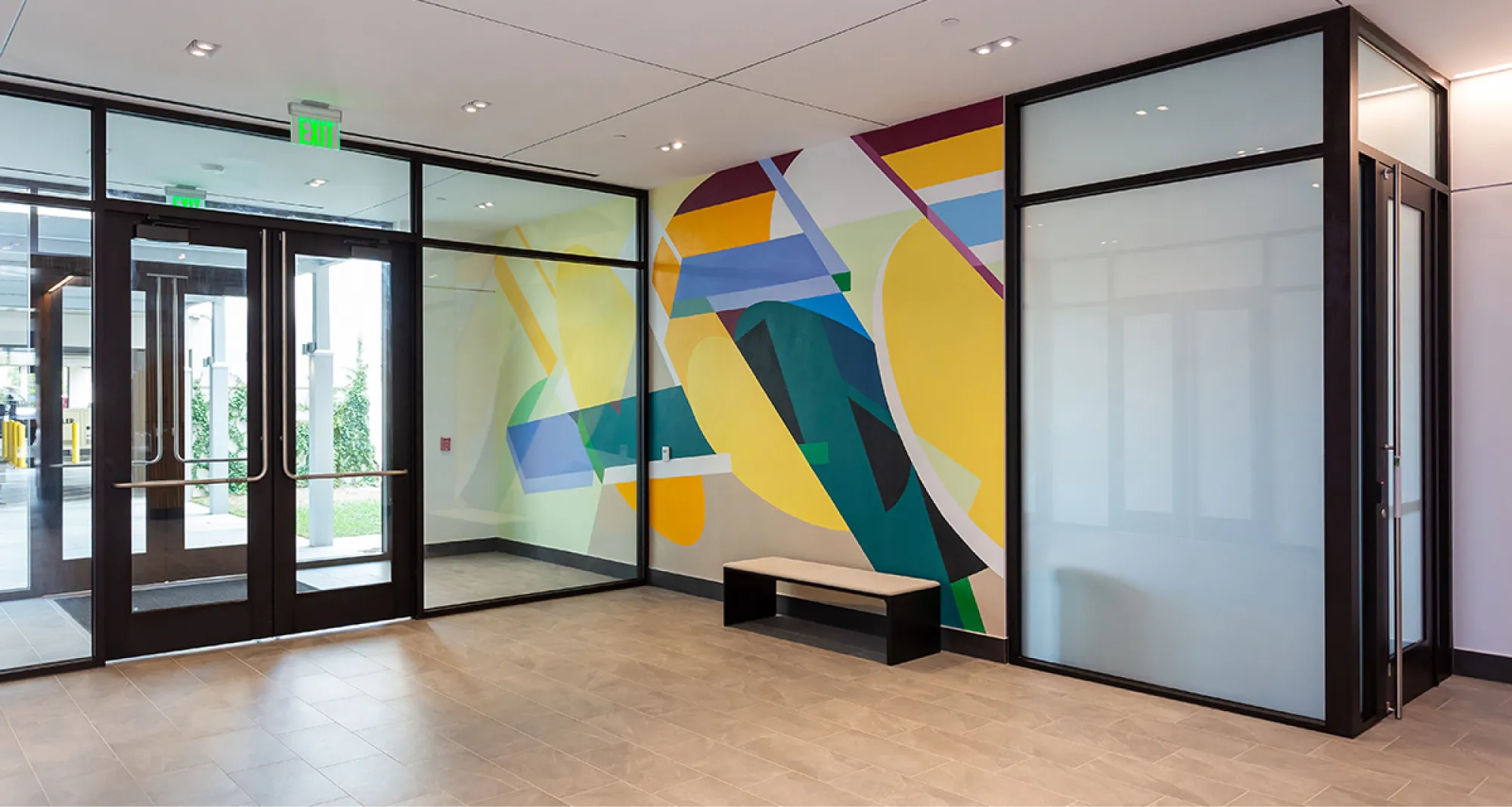 Bright abstract mural with bold geometric shapes decorating a modern lobby with glass doors