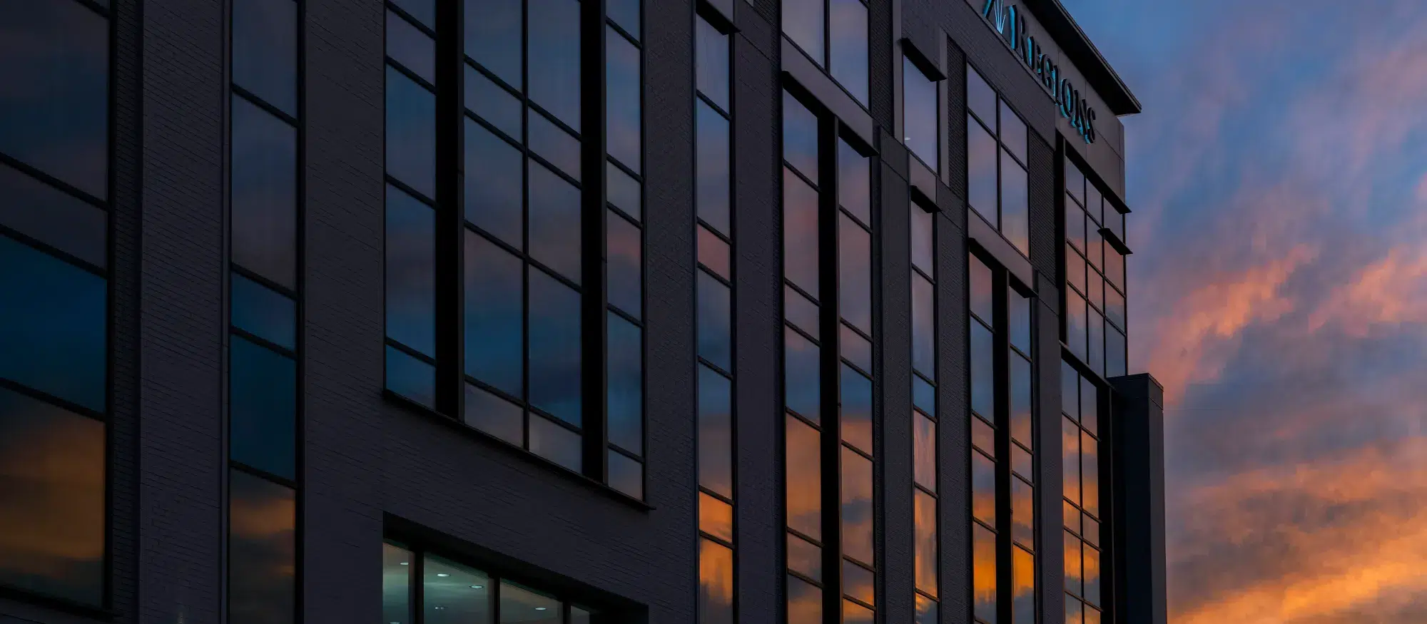 Glass office building reflecting the sunset sky, creating a dynamic, colorful exterior view