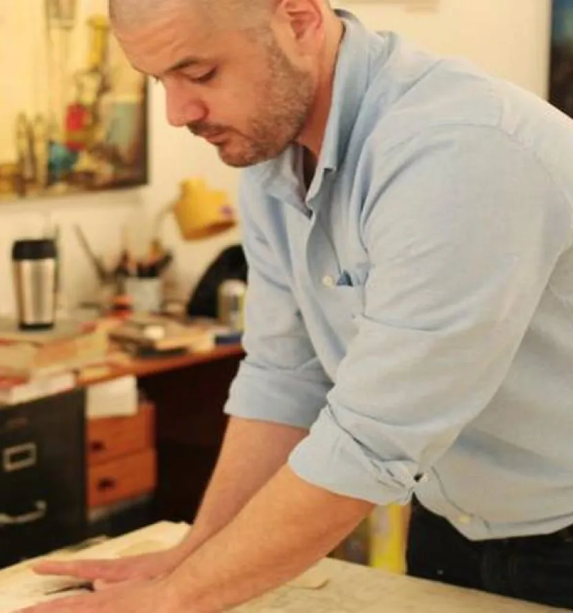 Artist Ollie Wagner in his studio, intently working on a new artwork at his desk