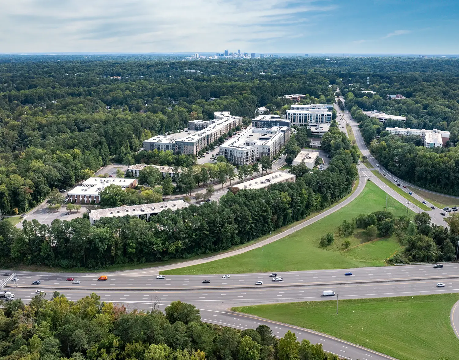 Aerial view of a mixed-use development surrounded by greenery and highways